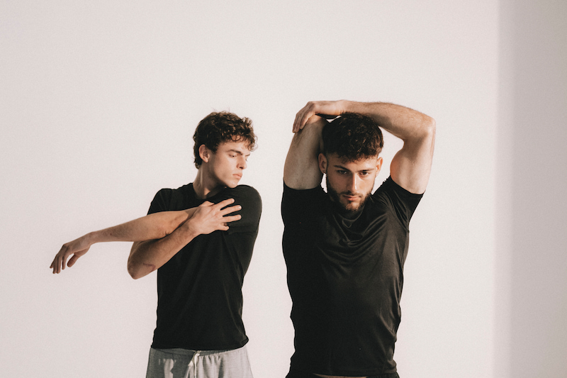 Dos hombres realizando movilidad de brazos como complemento al yoga