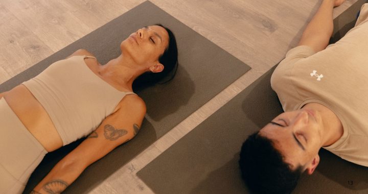 Dos personas descansando en Savasana durante una práctica de yoga.