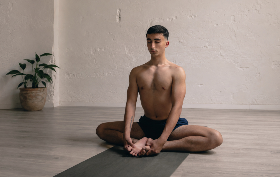 Persona sentada sobre una esterilla practicando respiración consciente con los ojos cerrados.